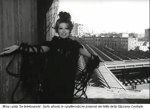 Mina canta 'Se telefonando'. Sullo sfondo le caratteristiche piramidi del tetto della Stazione Centrale